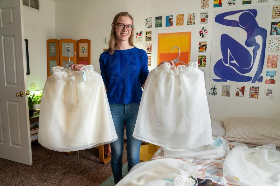 Julia LeKander holds skirts on hangers.