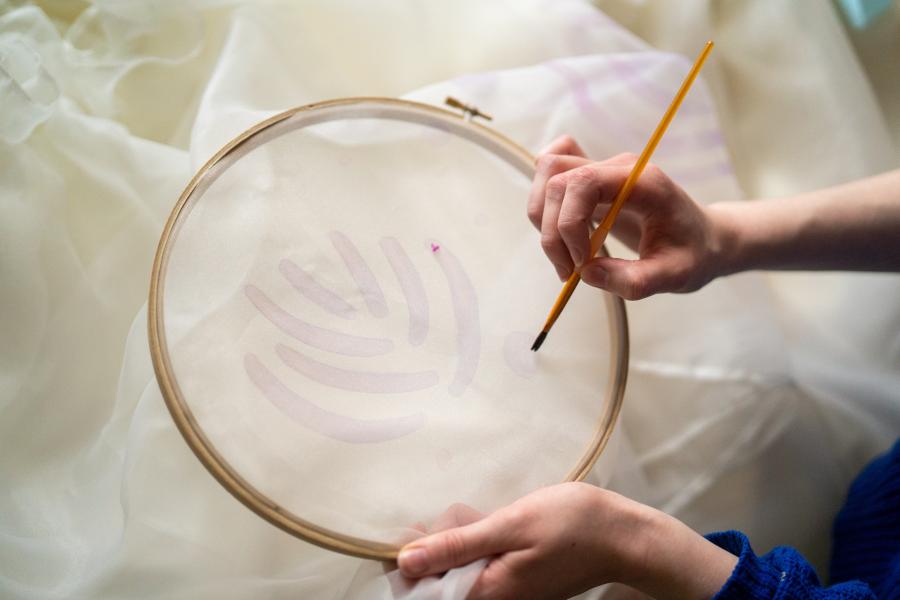 Julia LeKander paints designs on a skirt.