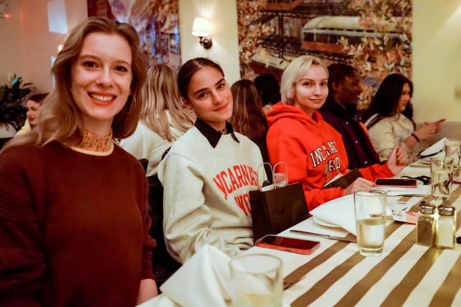 Three students sit together at a dinner table in a restaurant.