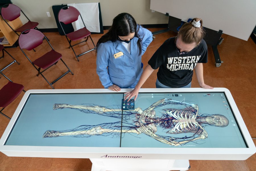 Two students looking at bones on the anatomage table.