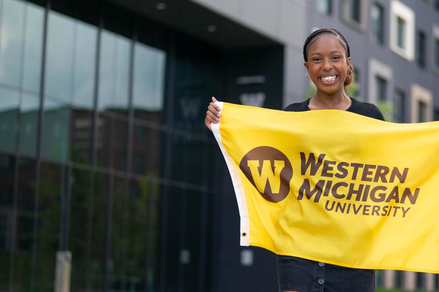 A student holding a Western Michigan University flag.