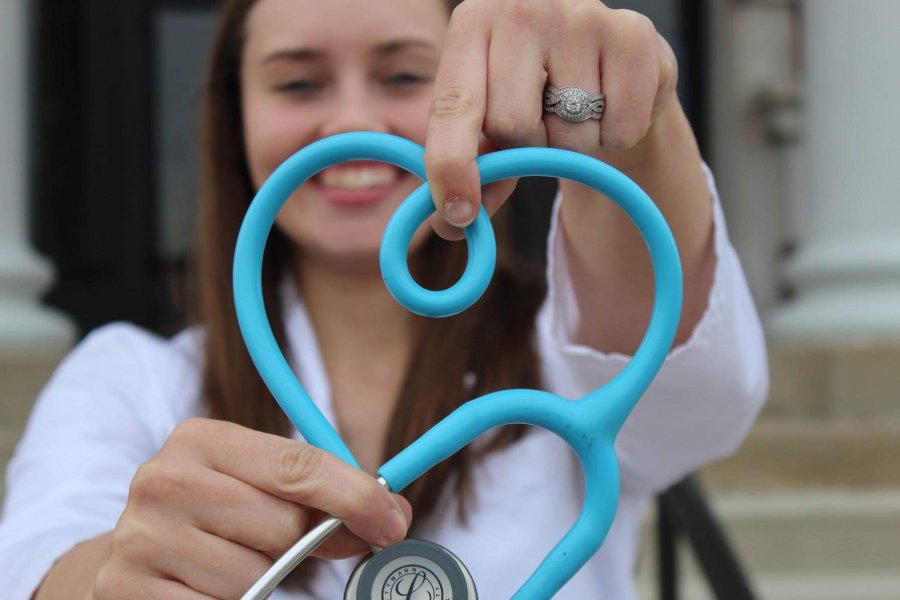 A person making a heart shape with a stethoscope.