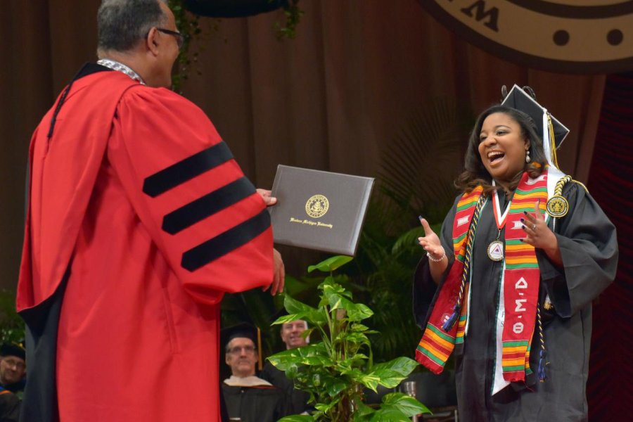 A smiling student preparing to shake Dr. Montgomery's hand and receive a diploma during commencement