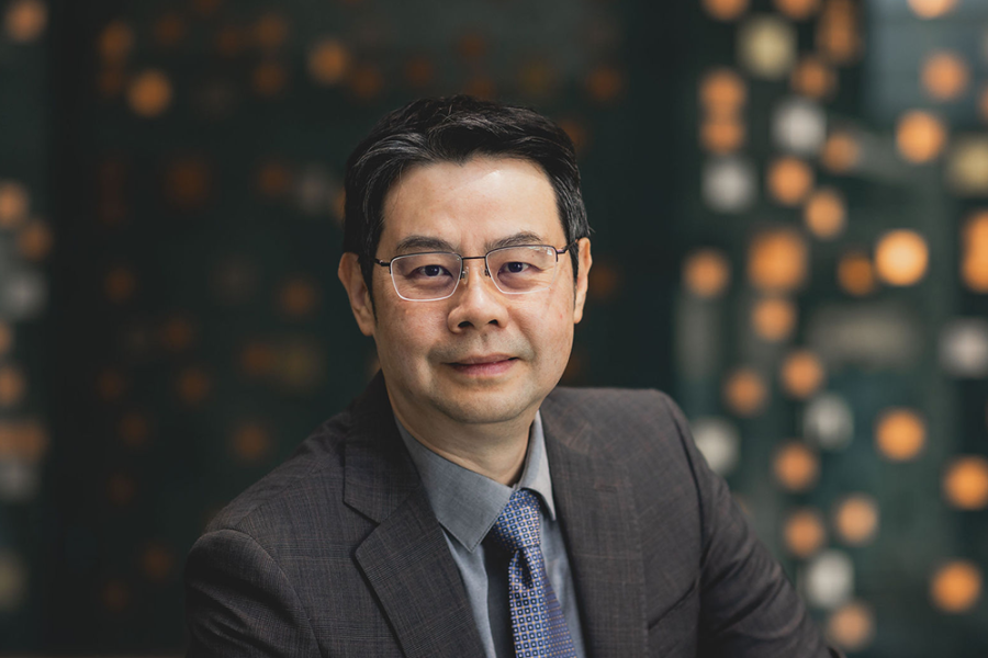 Professor Kuanchin Chen sitting in front of a glass and metal display.