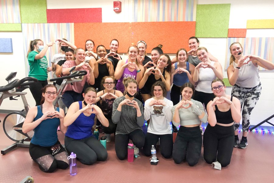 Cyclefit participants gathered together after a CycleFit class with instructor posing for a photo.