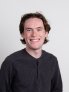 Eli Flak Head and shoulders professional photo wearing a gray pull over long sleeve shirt