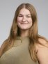 Mia Perleberg is smiling for a formal portrait in front of a light background. She is wearing a beige top and is smiling.