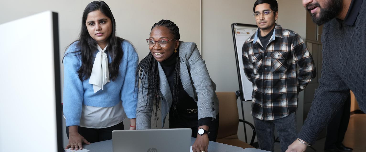 Graduate students working around a desktop