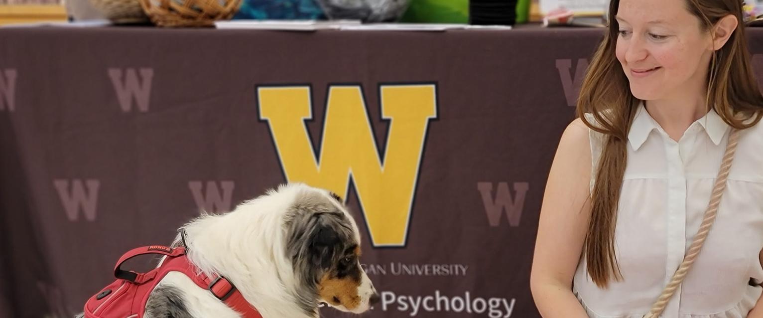 An image from the Applied Animal Behavior Practicum where Kat is looking lovingly at the program's mascot dog. 
