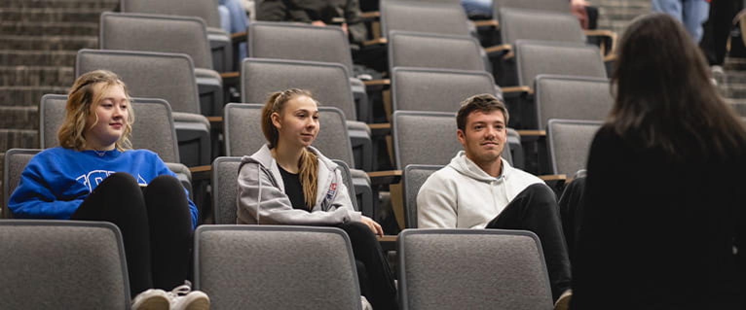 Students in a row listening to a faculty instructore.