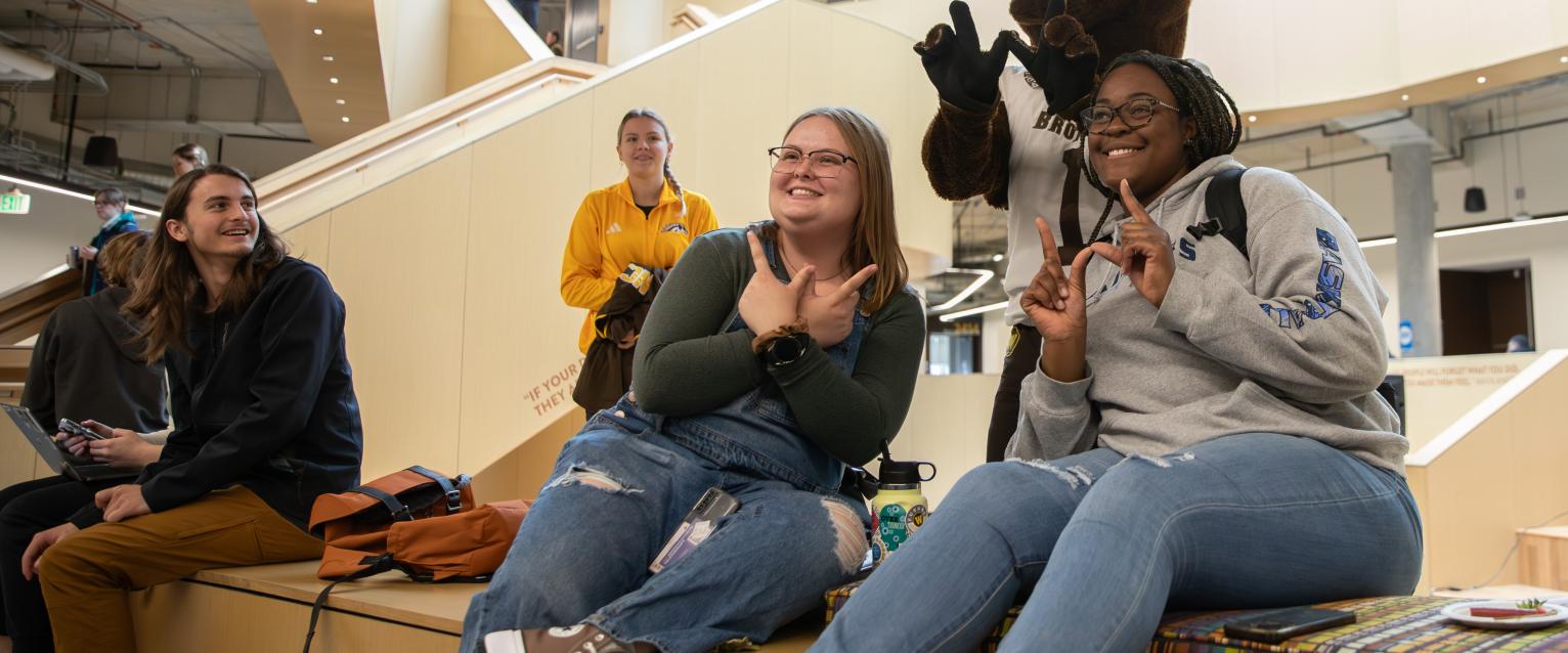 Two students in the Student Center with Buster Bronco showing the Western W on their hands.