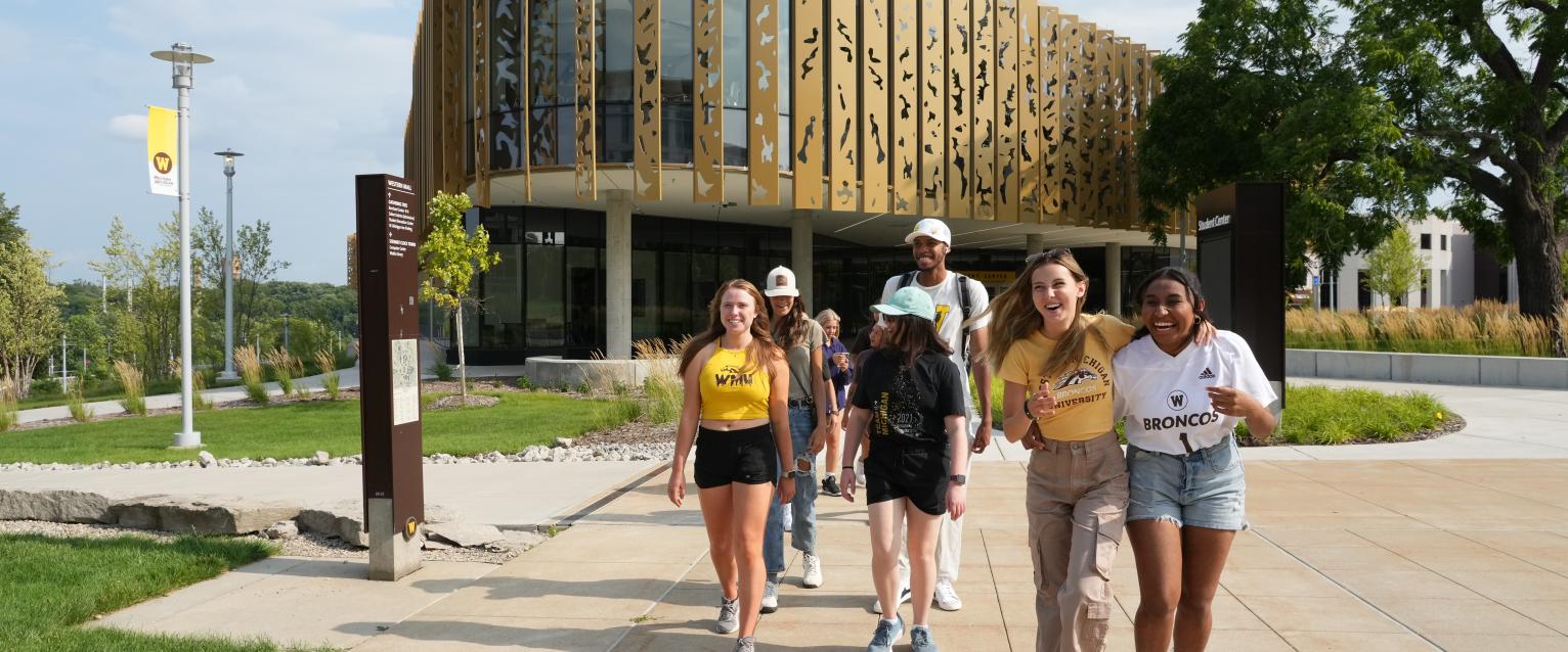 Student models explore outside the new WMU Student Center on a bright Summer day.