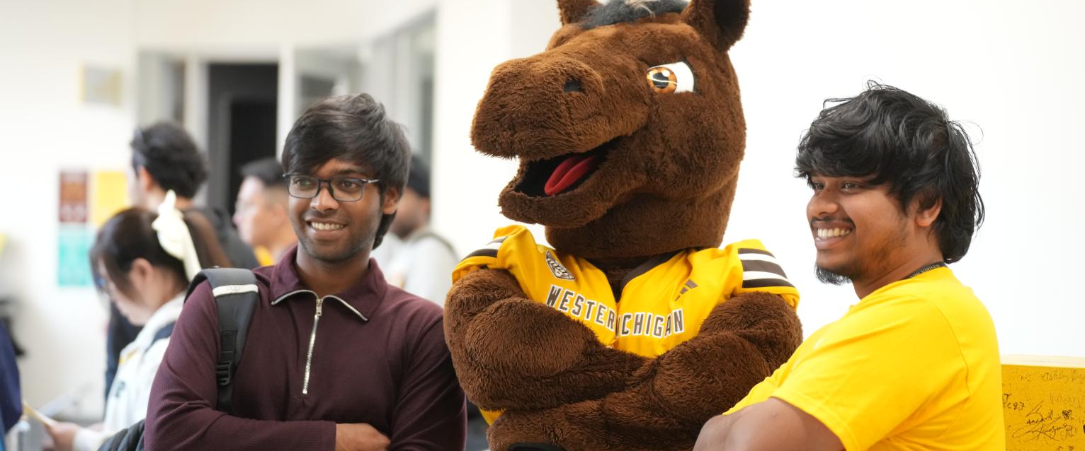 Two international students posing with Buster Bronco at orientation