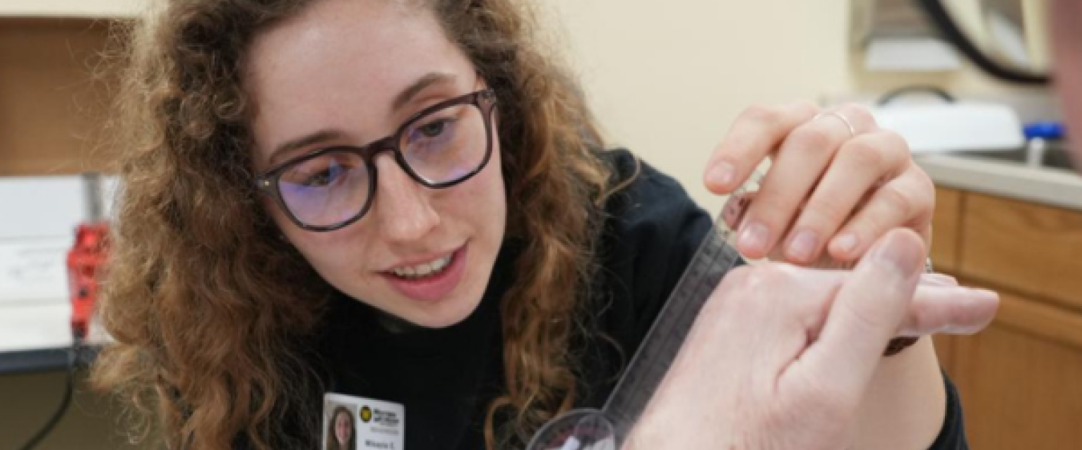 A WMU occupational therapy student, using a tool to take a measurement of a hand