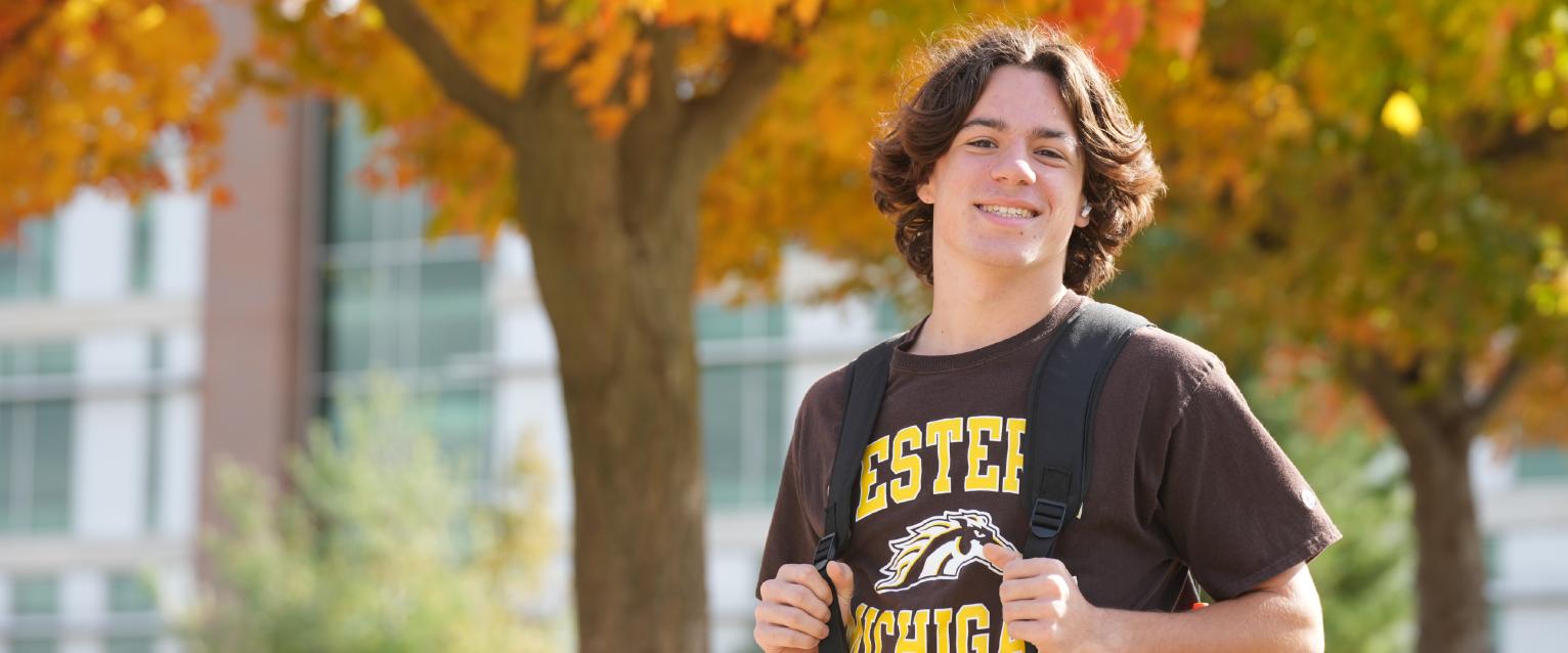 Young male student with backpack with a fall background