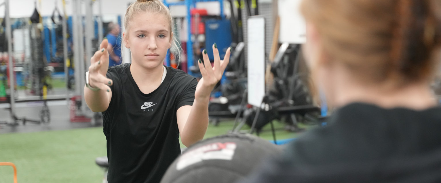 Girl throwing a weighted ball to a personal trainer