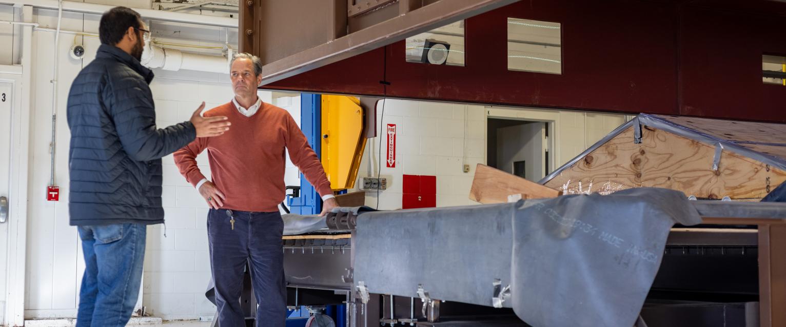Two men standing next to a machine. 