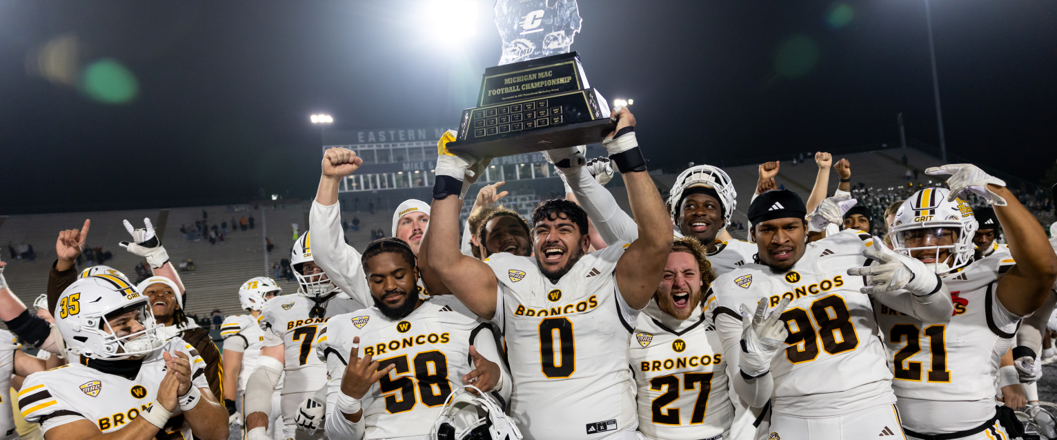 WMU football players hoist a trophy over their heads.