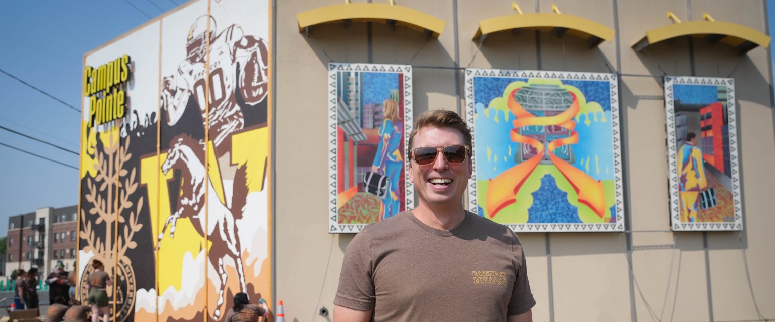 Brad Zenz smiles in front of his murals.