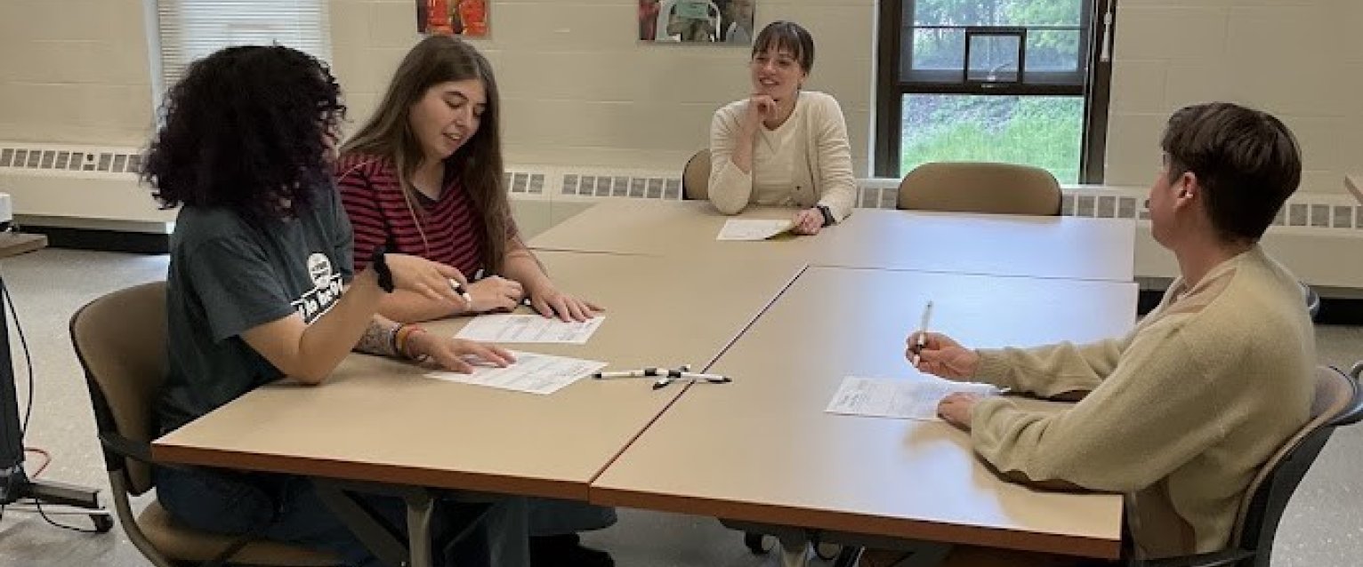 3 students and wellness coach sitting at a table, filling out goals worksheets