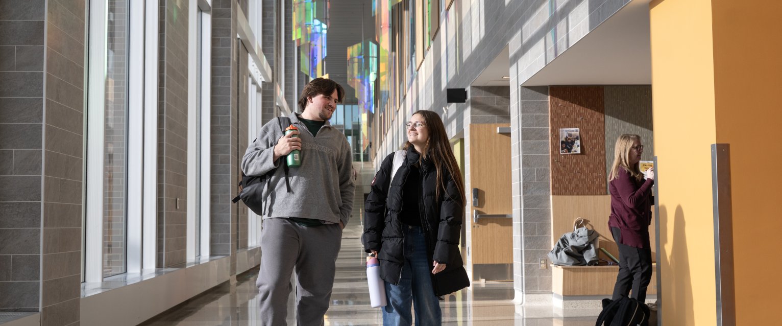 Two students walking beneath colorful, hanging glass sculptures in Sangren Hall.