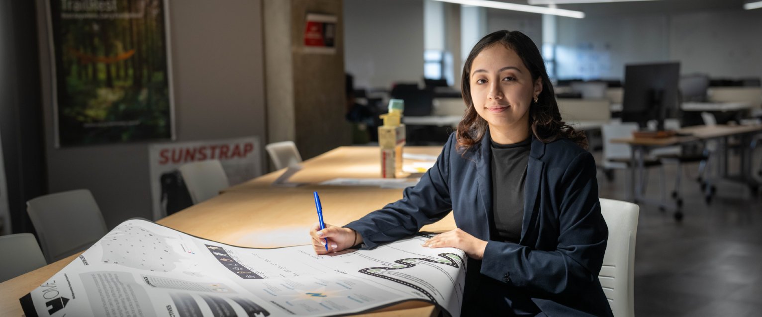 A WMU student working on a large document project at a creative work space.