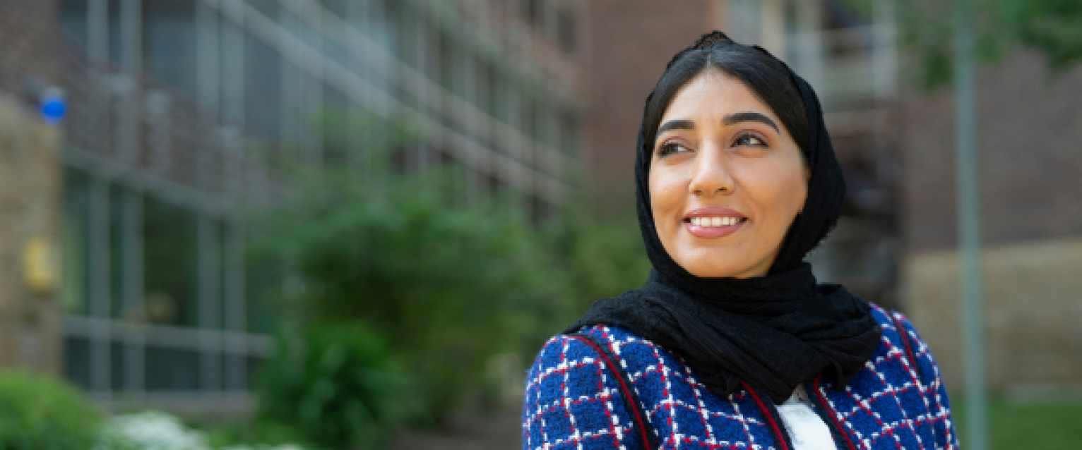 A female graduate student smiling in front of the college 