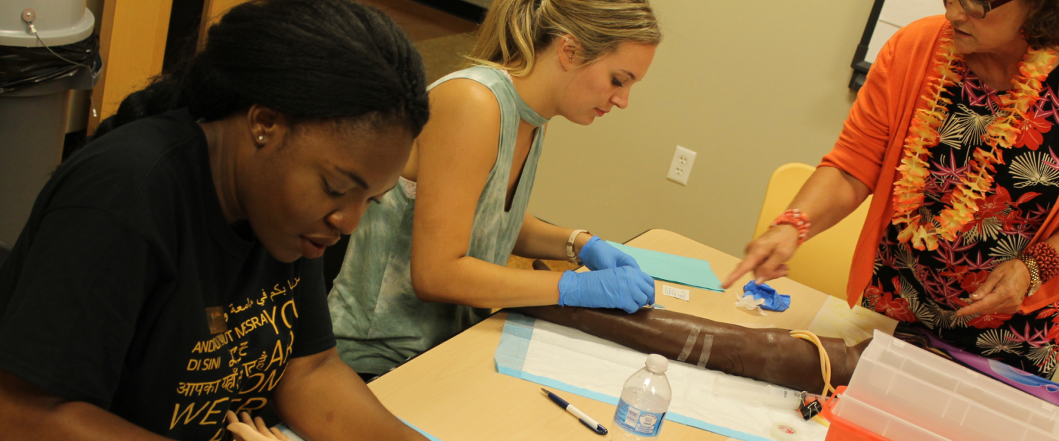 Two female nursing students practicing IV's in a lab.