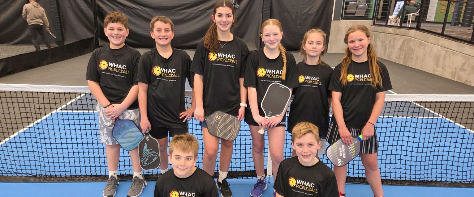 West Hills Kalamazoo Stampede youth pickleball team. Participants are in two rows wearing a black t-shirt with a bright West Hills logo printed on them.
