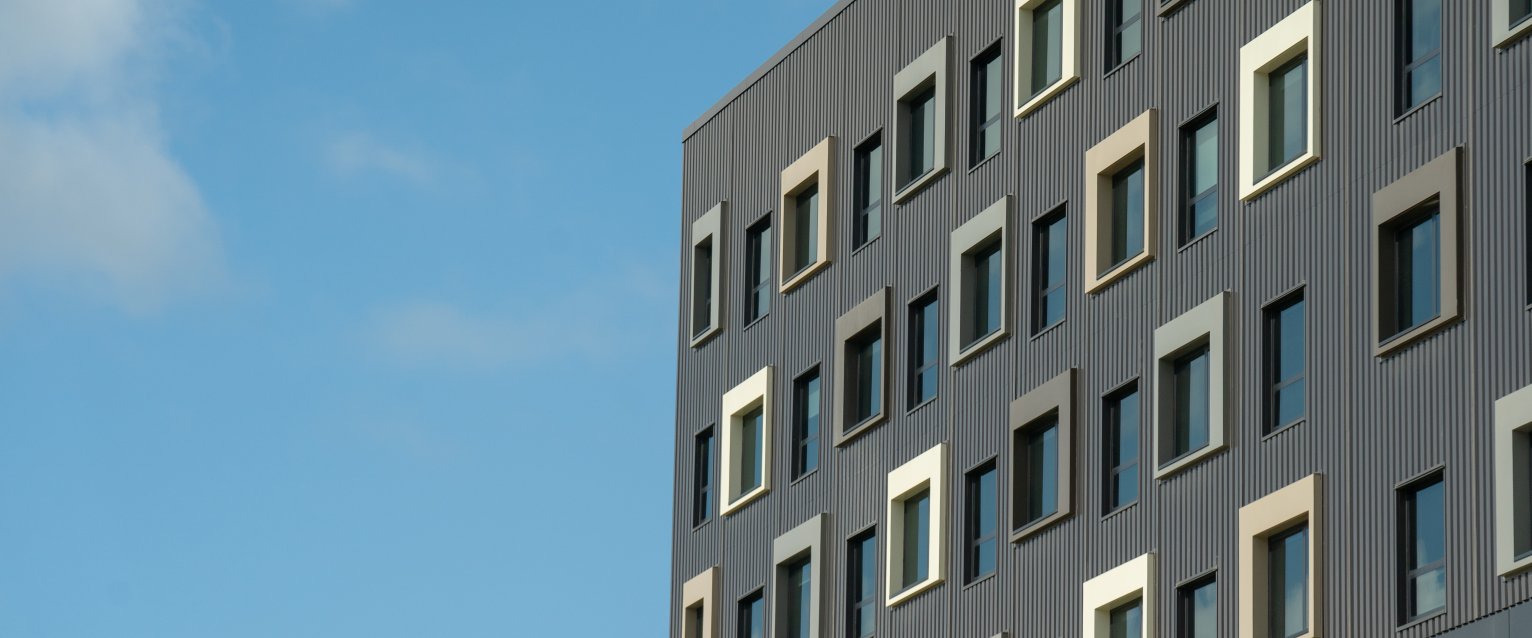 A modern, dark grey and brown campus apartment building with decorative square accents around the windows.