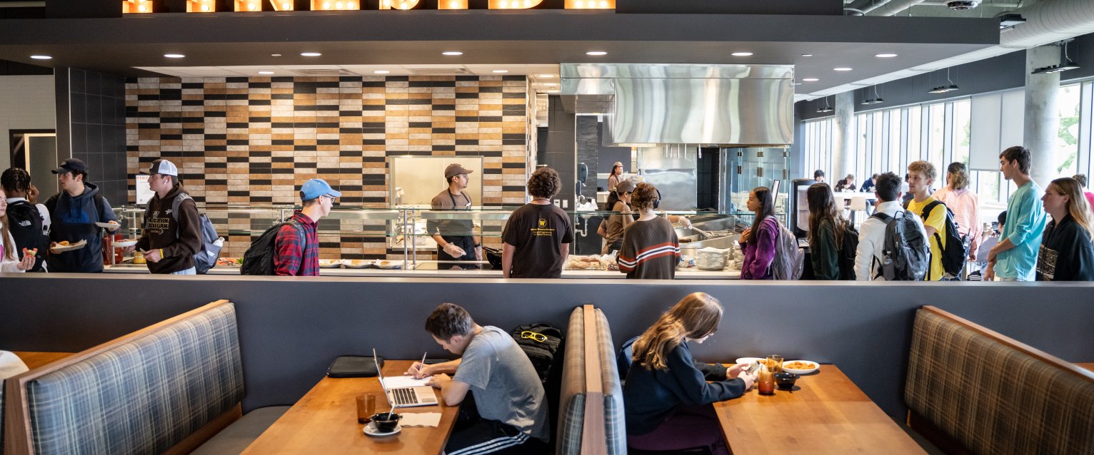 Students lining up around the Fireside dining venue and eating in large booths.