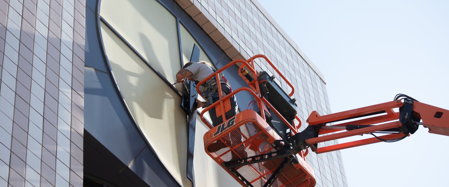 A maintenance services employees repairs the Waldo Library clock tower from a lift.