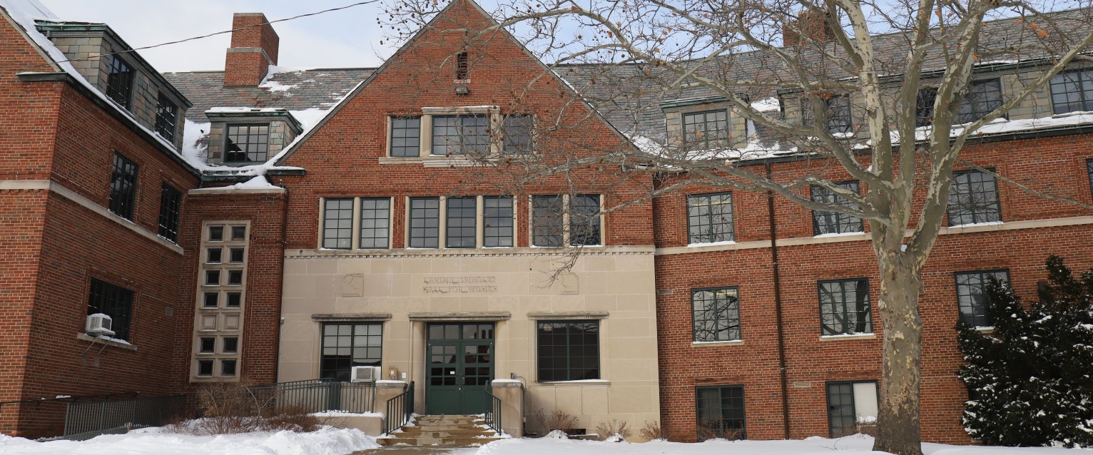 The front facade of a snow covered brick residence hall.