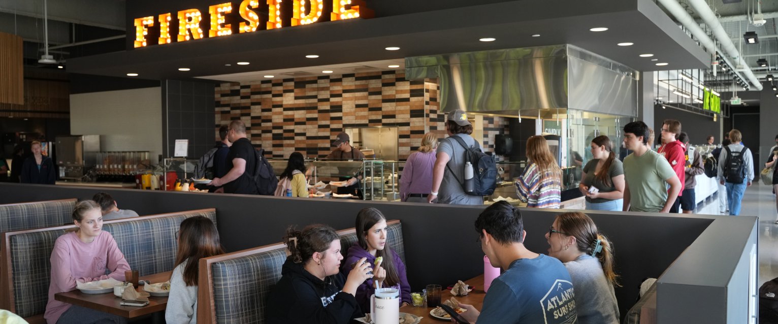 Students line up for food and eat together in large booths in the Student Center Dining facility.