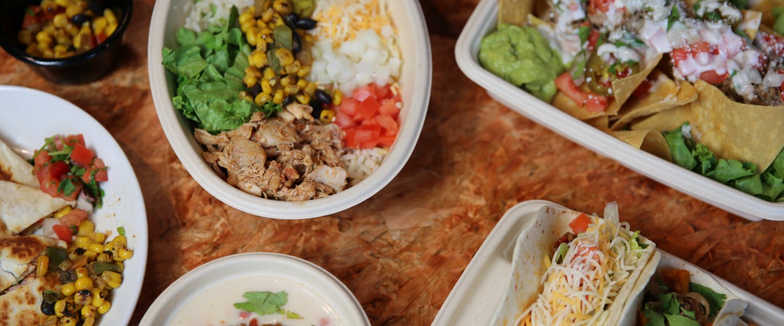 A display of dishes available at Fuego Verde, including tacos, burrito bowl, nachos, chips and queso.