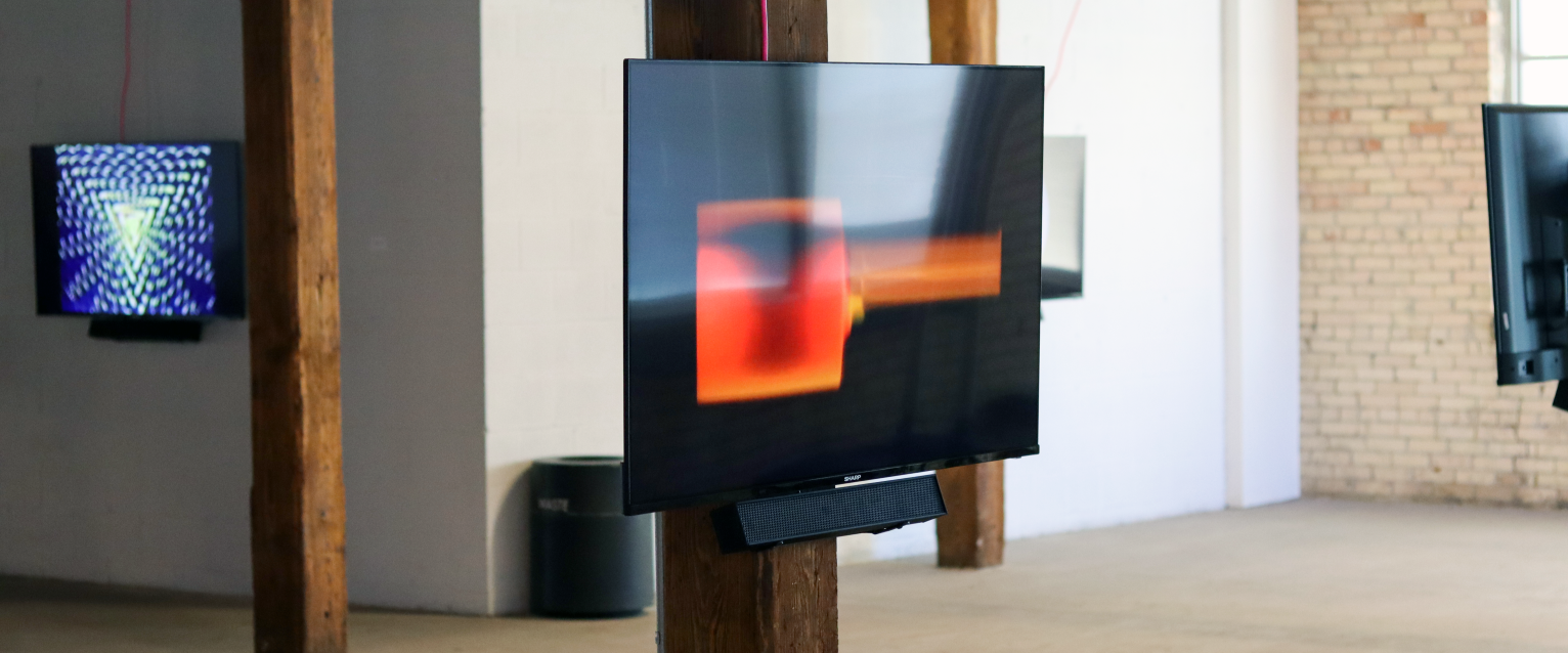 TV screen in art gallery with piece by Matthew Schlanger that has some red boxes on the screen.