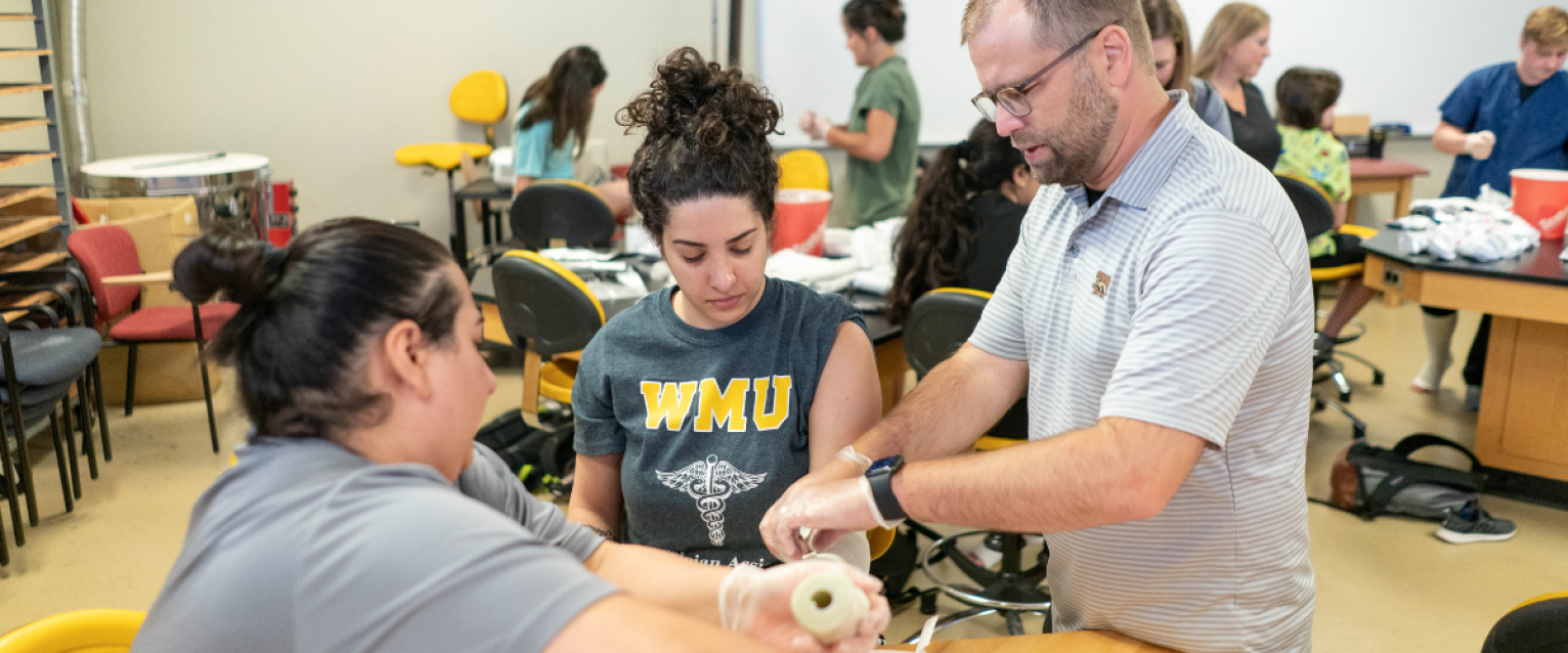 Physician Assistant professor demonstrating how to wrap an injured hand.