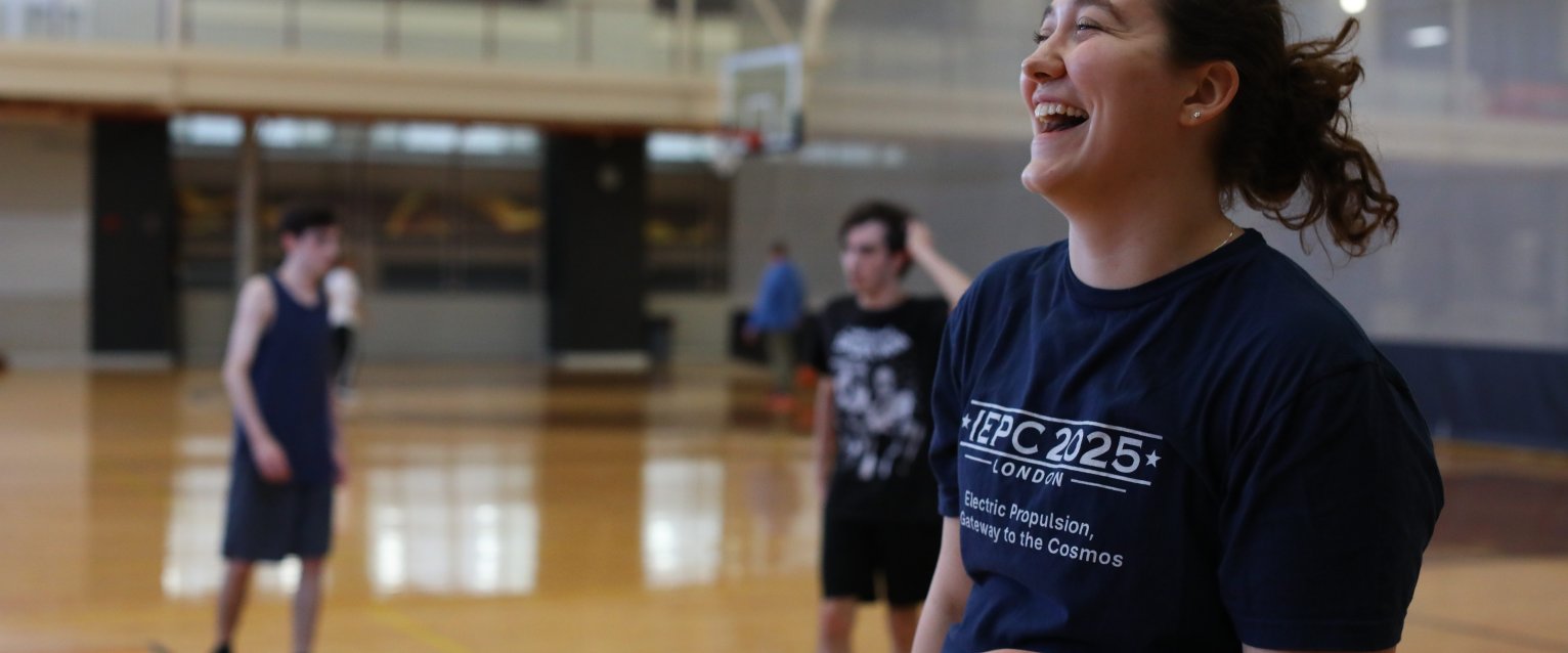 A Graduate student smiling and playing Volleyball at the Student Recreation Center.