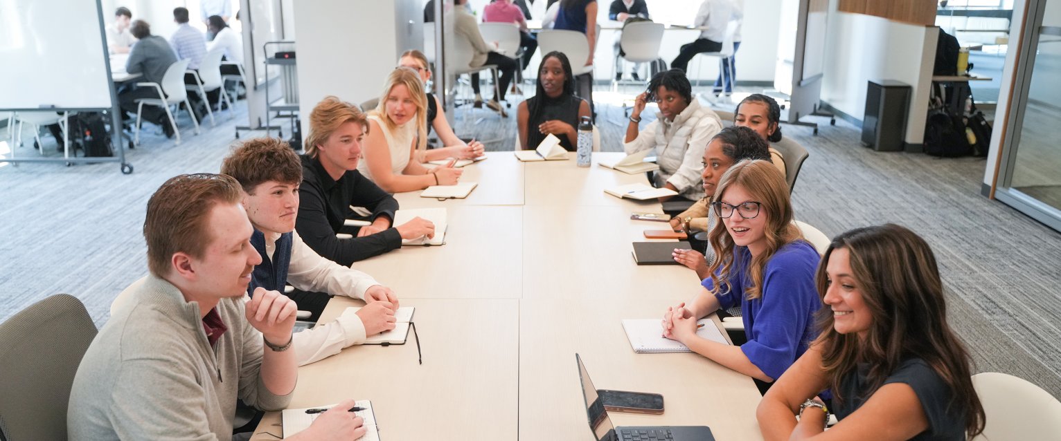 A group of students sitting together in front of a long table