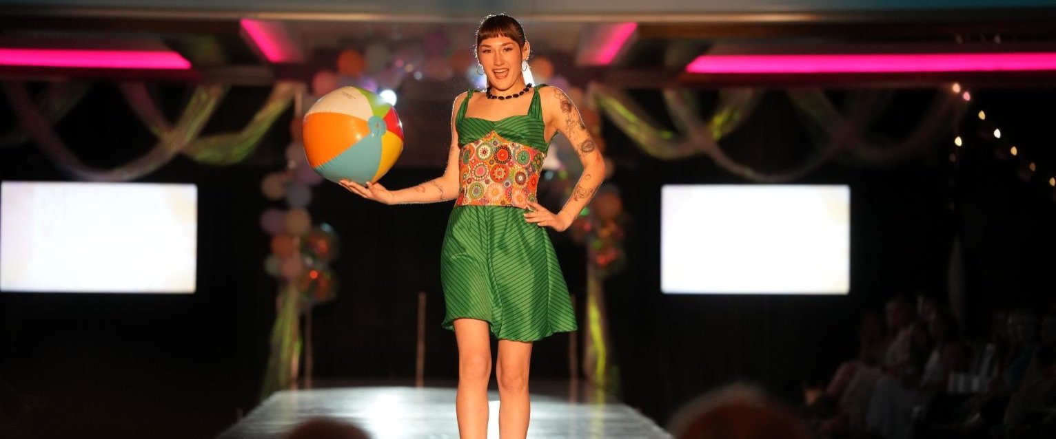 A student participates in a Western Michigan University registered student organization fashion, walking on a runway during a student fashion show..