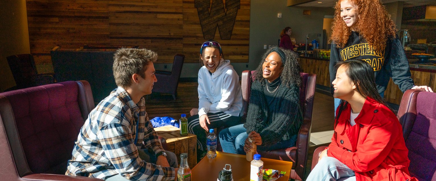 Students are gathered around the seating area inside Cafe 1903 with an assortment of beverages and snacks.