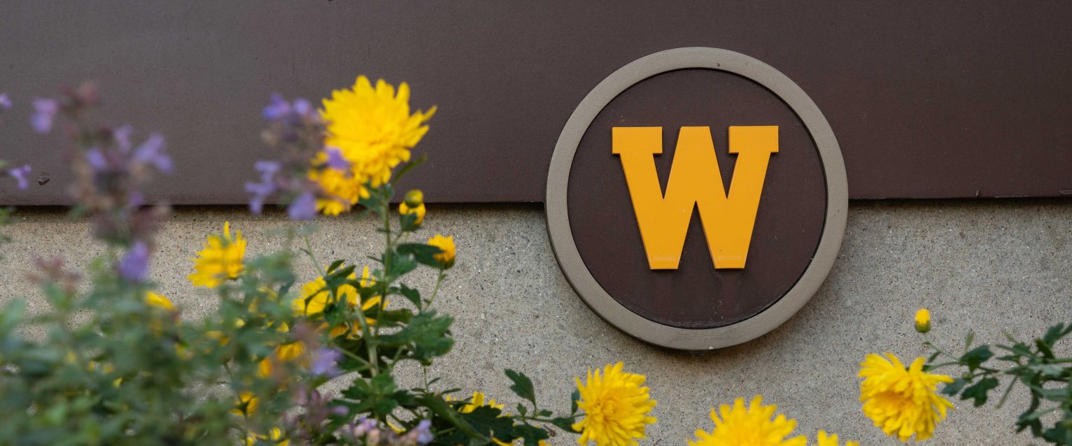 A cluster of flowers frame Western's W logo on the side of a building.