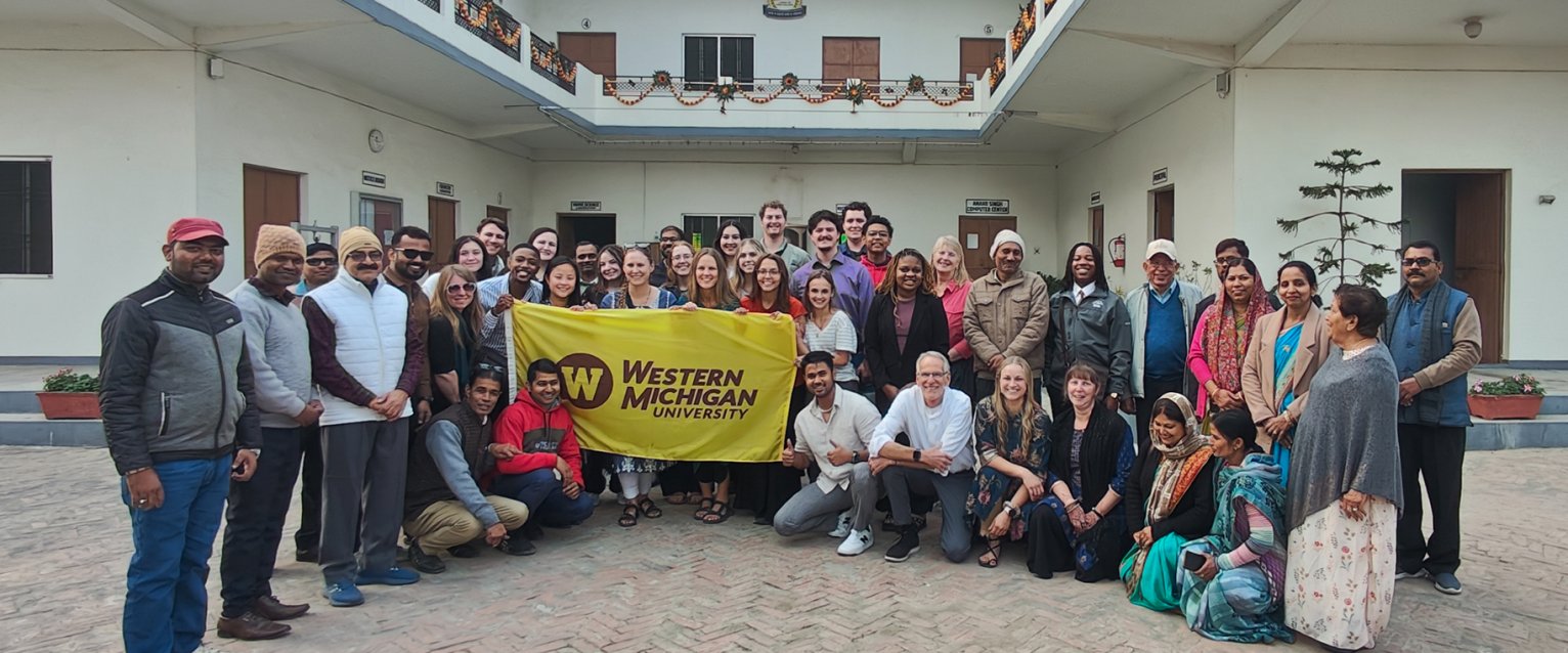 A group of study abroad students sitting in front of an Indian school