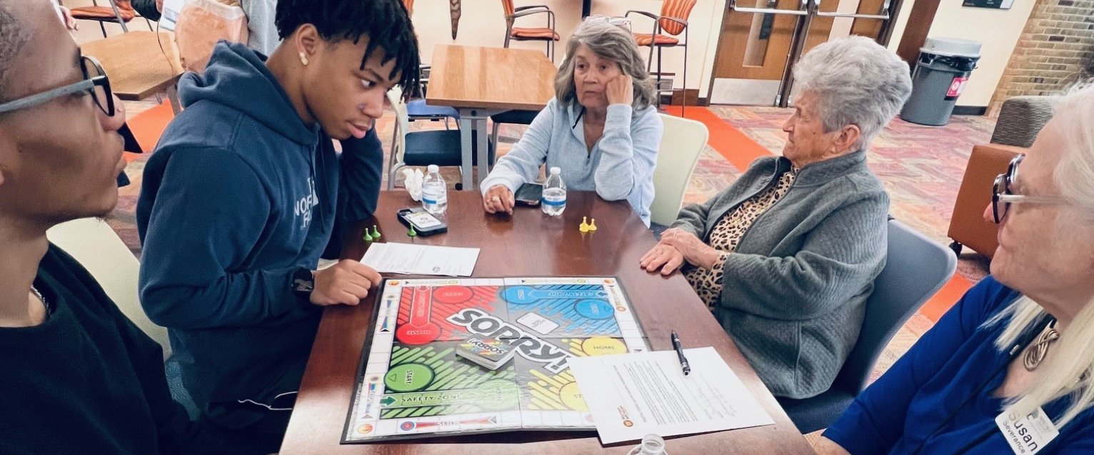WMU student volunteer playing board games with seniors from the Heritage Community in Kalamazoo.