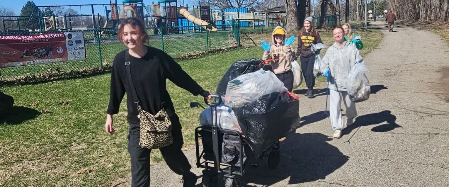 Group of WMU student volunteers hauling a wagon and bags of trash during the park cleanup in the Edison Neighborhood.