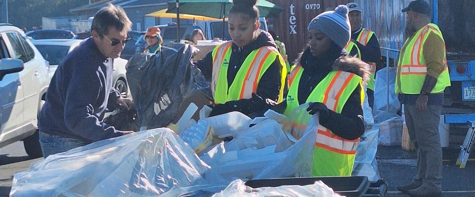 WMU student volunteers, wearing yellow vests while volunteering at the Kalamazoo River cleanup at Mayor's Riverfront Park.
