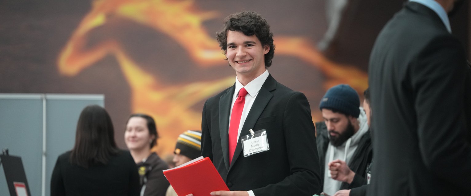A student at the Engineering Expo with a resume folder. 