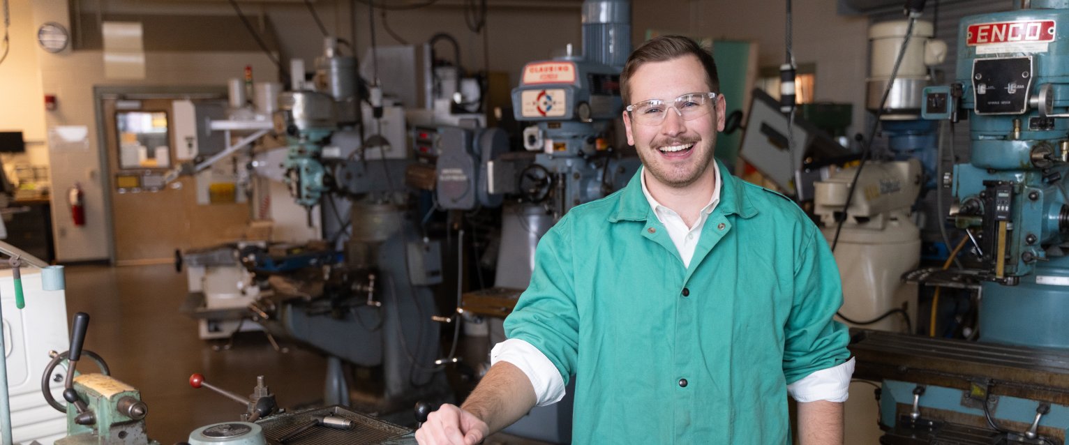 A graduate student with a manufacturing machine. 