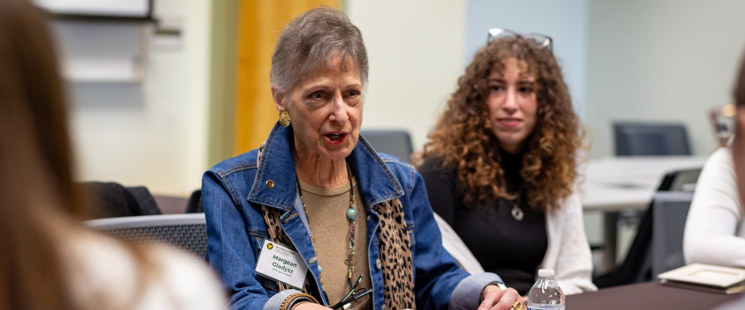 A WMU alumna sitting at a table with current students. 