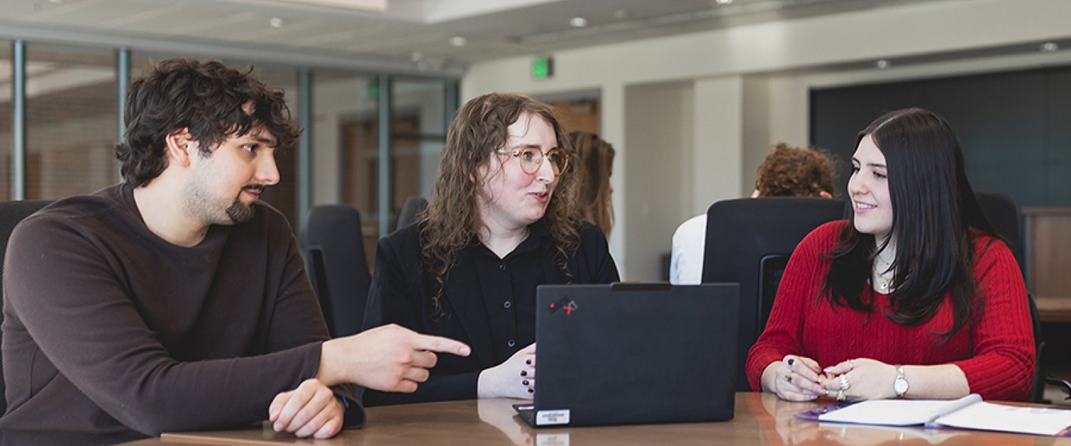 two students and a faculty member discussing class materials 